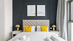 A modern hotel room with a large bed, two bedside tables with lamps, and artwork on the wall. - Silkhaus Luxurious New Tower With Pool Gym (Dubai)