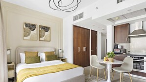 Una camera d'hotel moderna con un letto grande, comodini, un piccolo tavolo da pranzo e un angolo cottura.