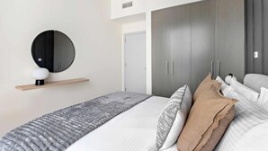 Ein modernes Schlafzimmer mit einem Bett, einem runden Spiegel, einem Kleiderschrank und einem Regal mit einem kugelförmigen Gegenstand.