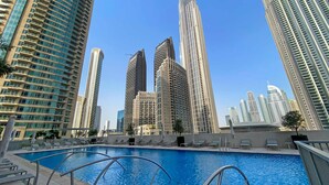 Ein Swimmingpool mit Liegestühlen, umgeben von Hochhäusern.