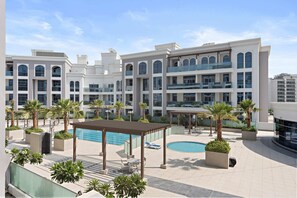 A modern hotel with a rooftop pool, outdoor seating, and palm trees. - Silkhaus Modern In-house Kitchen Pool Art Gardens (Dubai)