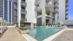 A modern apartment building with a rooftop pool, outdoor seating, and a clear blue sky. - Silkhaus Modern in JVC Convenient Gym Pool (Dubai)