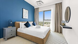 A bedroom with a large bed, a nightstand, a wall-mounted shelf, a ceiling light, a window with curtains, and a city view. - Silkhaus New Tower in the Heart of Downtown (Dubai)