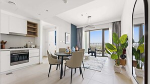 A modern kitchen with white cabinets, a built-in oven, and a dining area with a round table and chairs. - Silkhaus New Tower in the Heart of Downtown (Dubai)