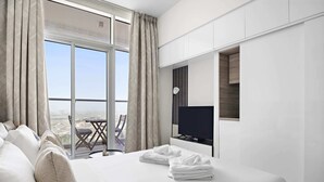 A modern hotel room with a large bed, a flat-screen TV, and a balcony with a city view. - Silkhaus Luxurious Studio in Studio One Tower (Dubai)
