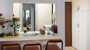 A small kitchen with a dining area, a coffee maker, a wine bottle, and a vase with flowers. - Old Bridge Apartment (Firenze)