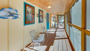 A covered porch with wooden flooring, metal chairs, and a wooden railing. - Riverside Retreat w/ Screened Porch: 6 Mi to Taos! (Taos)