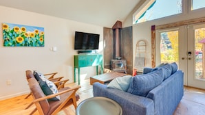 A living room with a sofa, chairs, a television, a painting, and a fireplace. - Riverside Retreat w/ Screened Porch: 6 Mi to Taos! (Taos)