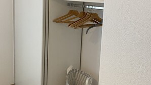 Un closet amplio con perchas de madera y una cesta a rayas.