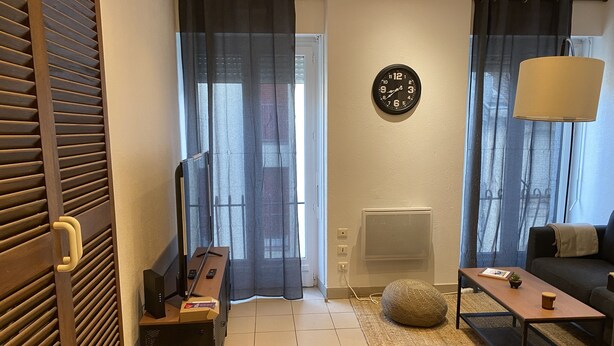Una sala de estar con televisor, sofá, mesa de centro y cortinas.