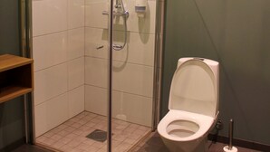 A modern bathroom with a glass-enclosed shower, a toilet, and a hand dryer. - KRS LIVE Hotel (Kristiansand)