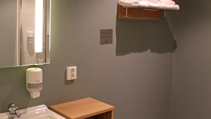 A bathroom with a sink, mirror, towel rack, and a shelf with toiletries. - KRS LIVE Hotel (Kristiansand)