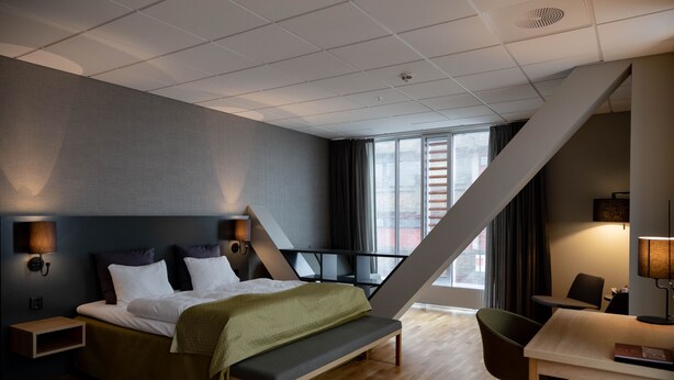 A modern hotel room with a bed, bench, desk, and chair. - KRS LIVE Hotel (Kristiansand)
