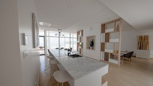 Una cocina moderna con una isla de mármol, taburetes de bar y un comedor con vistas.