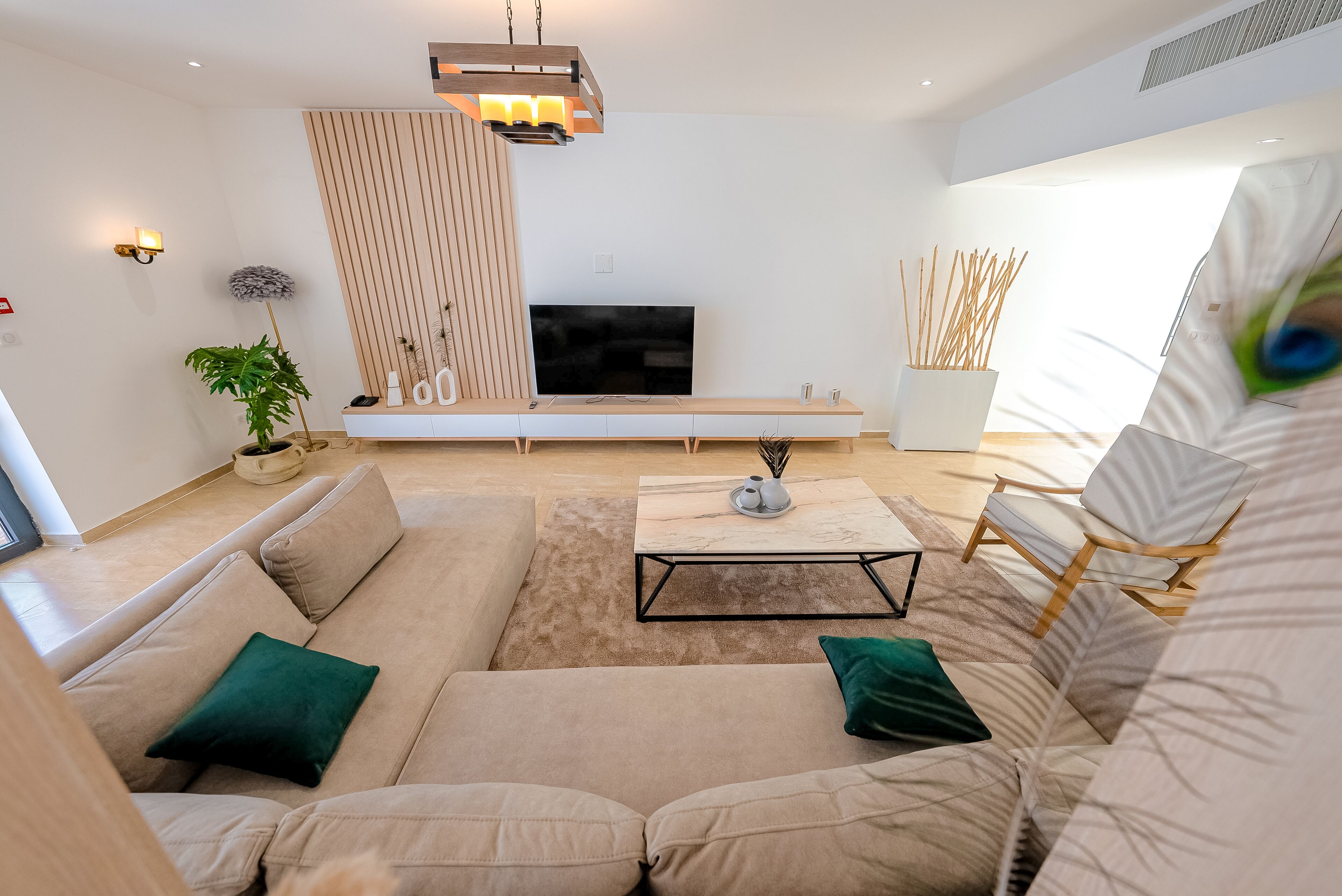 Ein modernes Wohnzimmer mit einem beigefarbenen Sofa, einem Couchtisch und einem Fernseher.