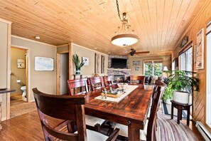 Une salle à manger en bois avec une grande table, des chaises et une cheminée.