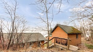 A wooden cabin with a green roof, a staircase leading to a porch, and a surrounding wooded area. - Water's Edge on Lake Vermilion  (Tower)