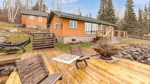A wooden cabin with a deck, outdoor seating, and a stone foundation. - Water's Edge on Lake Vermilion  (Tower)