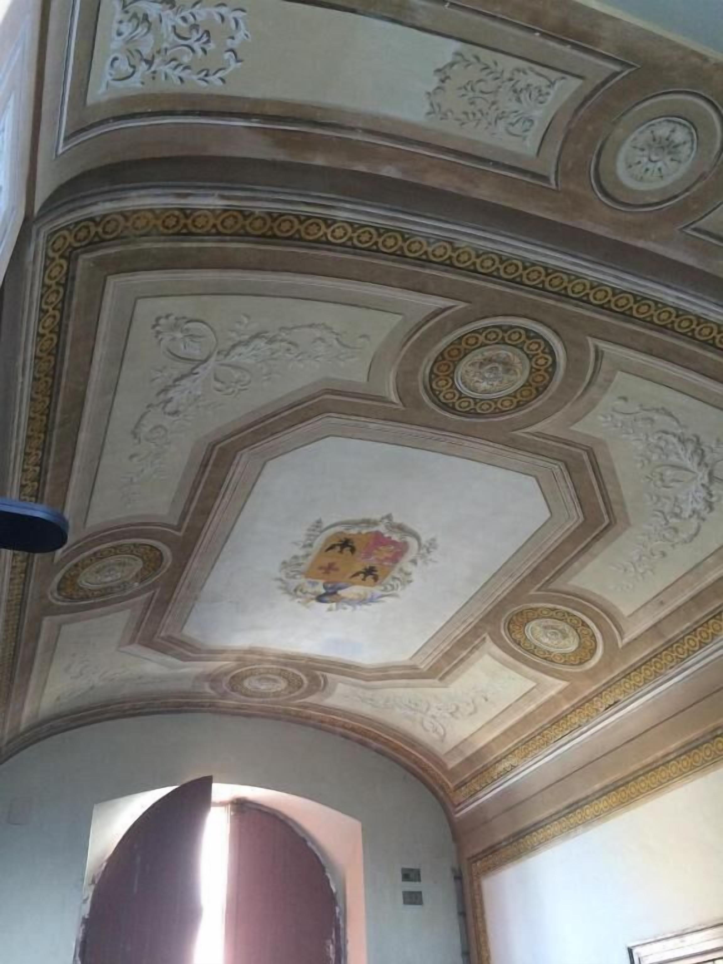A ceiling with intricate patterns and a central emblem.