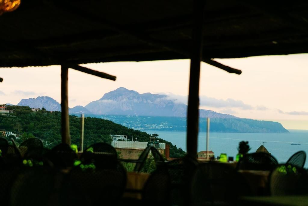 A view from a covered area with a mountain and sea in the background.