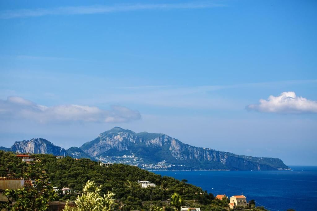 Un paysage côtier avec une montagne imposante en arrière-plan, un ciel dégagé et une vue sur la mer.
