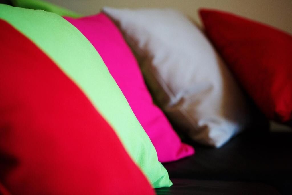 A close-up of a bed with pillows in red, green, and white colors.