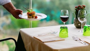 A table set with a plate of food, wine glasses, and cutlery.