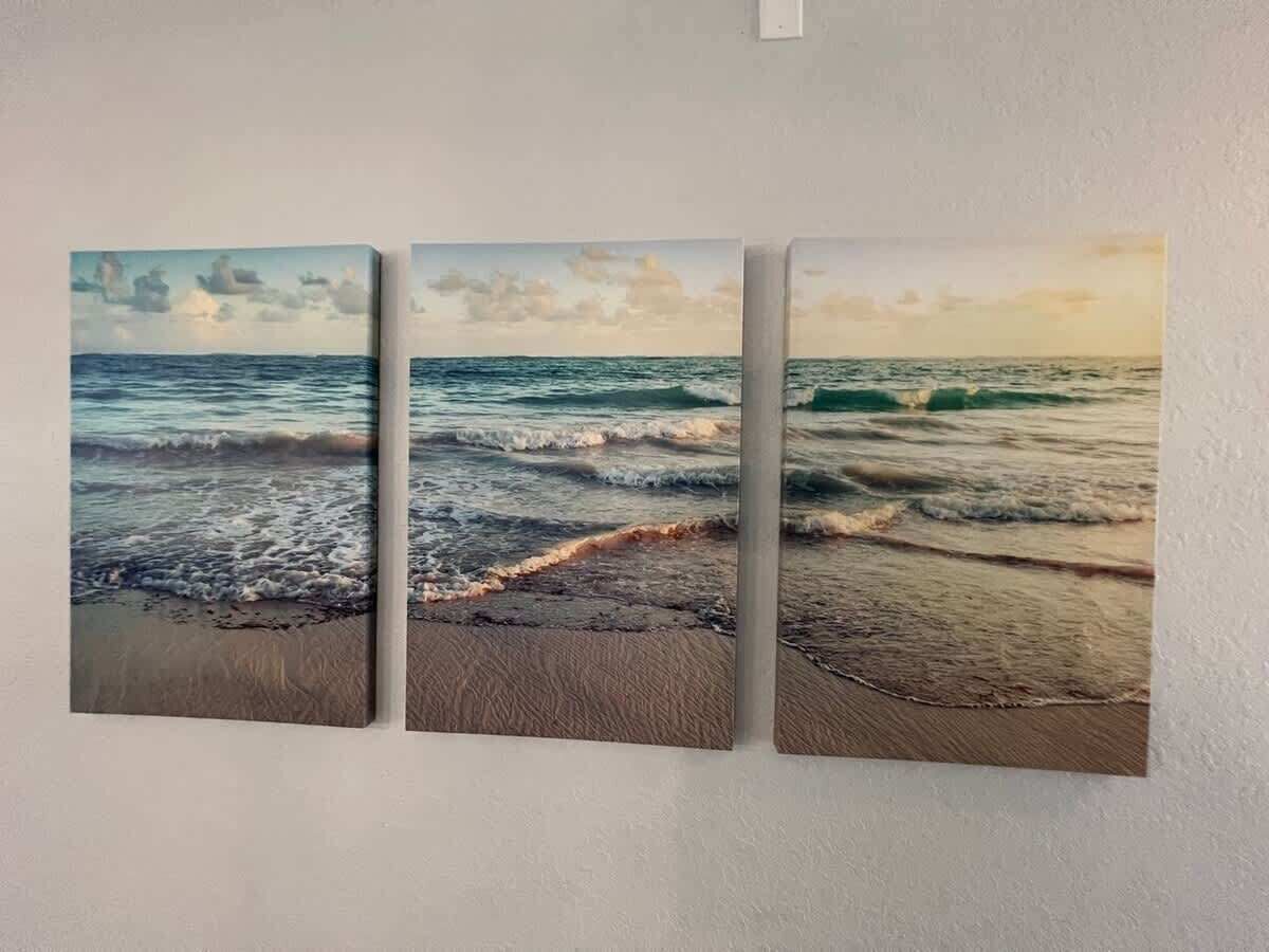 Un mur orné de trois panneaux représentant une scène de plage.