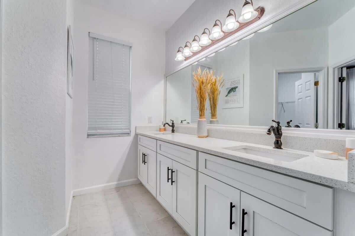 A modern bathroom with a large mirror, two sinks, and a vanity with cabinets.