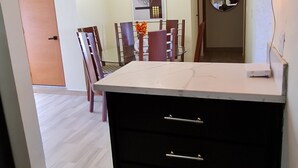 A modern kitchen with a central island, pendant lighting, and a dining area in the background. - Central Apartment Facing the sea (Puerto Plata)