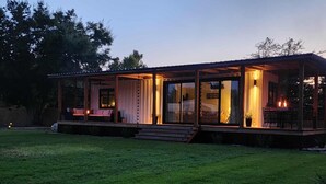 A modern, open-plan house with a covered patio and a fire pit area. - One of a kind Romantic Luxe Retreat, 8 Minutes to Emerald Beach, Outdoor Haven (Navarre)