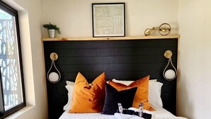 A bed with striped bedding, multiple pillows, a bedside table with a lamp, and a framed artwork above the bed. - One of a kind Romantic Luxe Retreat, 8 Minutes to Emerald Beach, Outdoor Haven (Navarre)