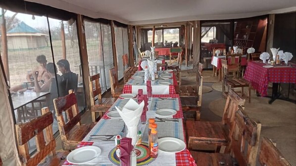 A dining area with wooden tables and chairs, red and white checkered tablecloths, and a rustic interior.