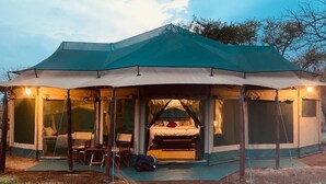 A tented accommodation with a bed, seating area, and a view of the surrounding landscape. - Osero Serengeti Luxury Tented Camp (Serengeti)