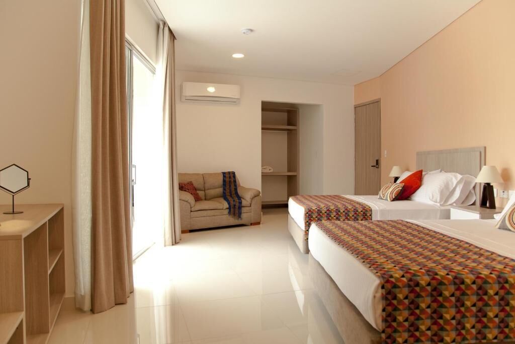 Habitación de hotel con dos camas, un sofá, un escritorio y un armario.