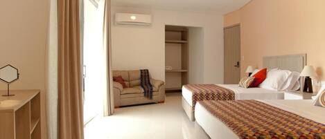 Habitación de hotel con dos camas, un sofá, un escritorio y un armario.