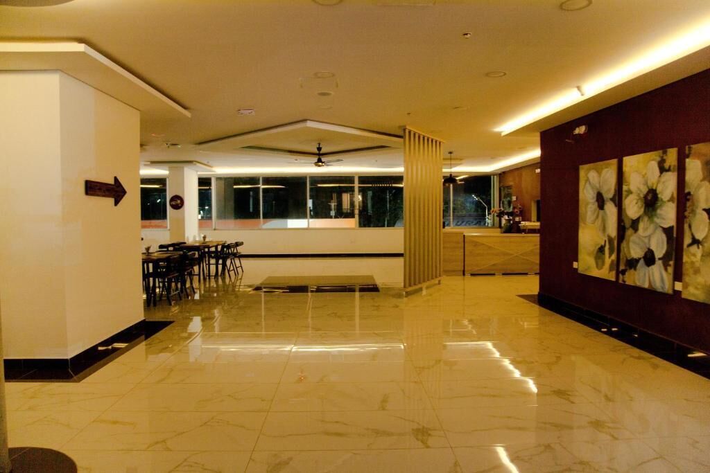 A hotel lobby with a marble floor, a reception desk, and a dining area.