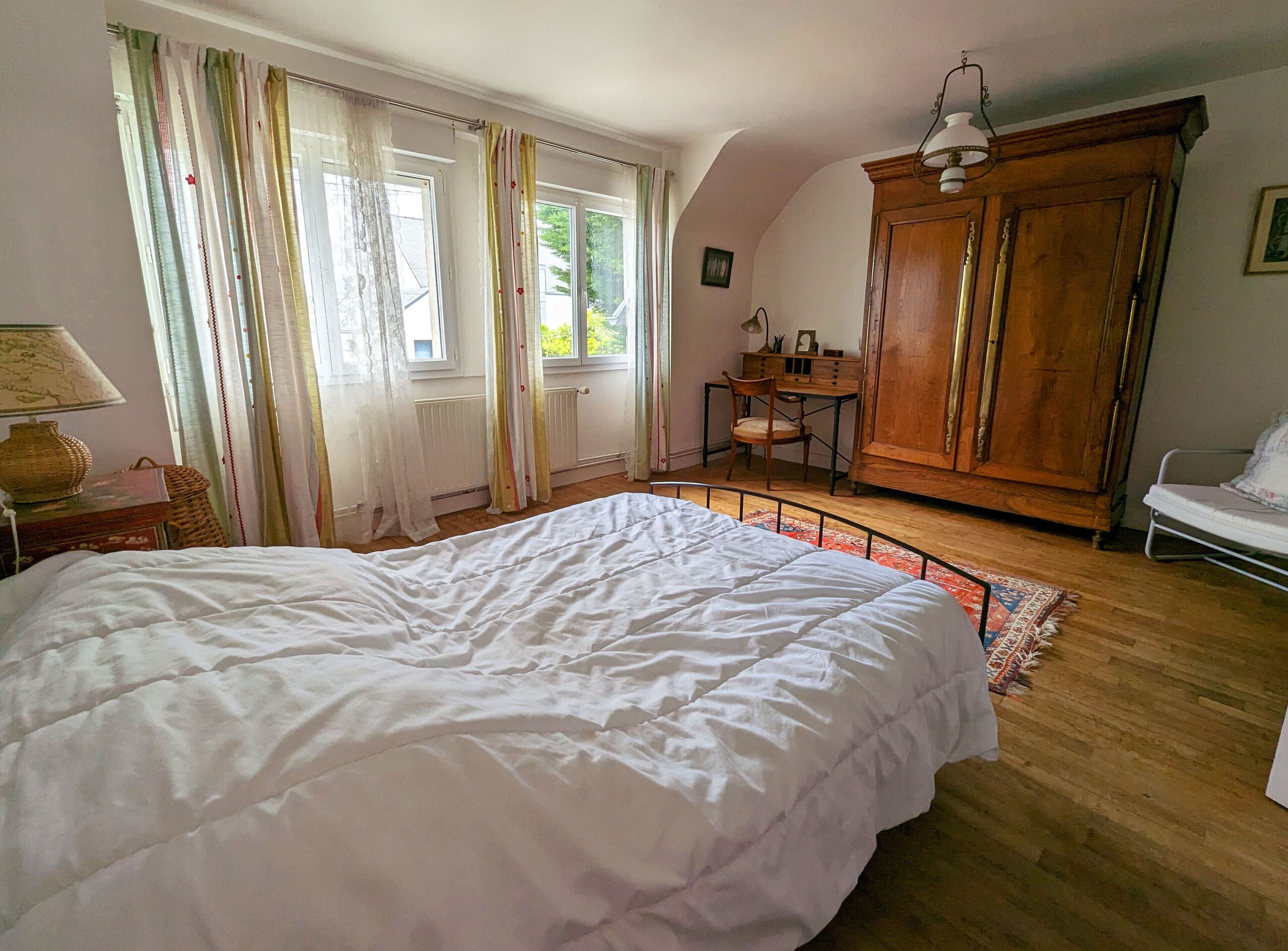 Ein Schlafzimmer mit einem großen Bett, einem Holzschrank und einem Schreibtisch mit Stuhl.
