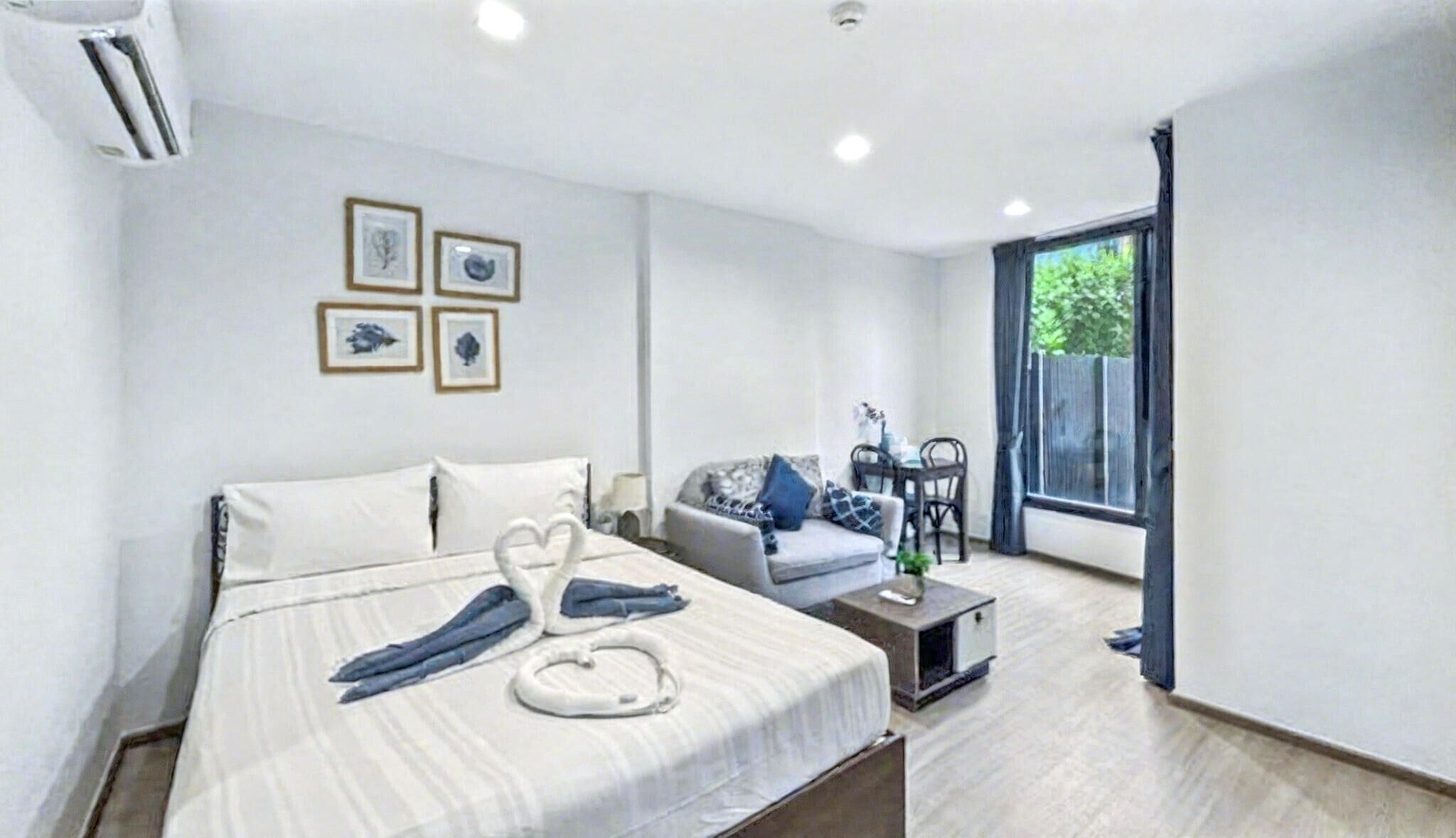 A hotel room with a bed, a sofa, a small table, and a window.