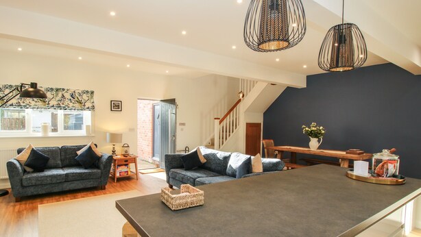 A spacious living area with a central island, a staircase, and a dining area. - The Caradoc (Shrewsbury)