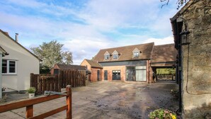A spacious courtyard with a wooden gate, a brick building with large windows, and a stone wall. - The Caradoc (Shrewsbury)
