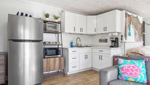 Una cocina moderna con armarios blancos, un refrigerador de acero inoxidable, un horno empotrado y un microondas.