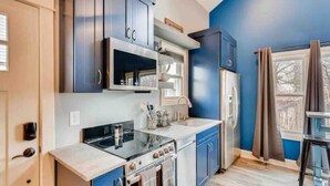 A modern kitchen with blue cabinets, a stainless steel refrigerator, and a built-in oven.