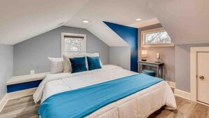 A bedroom with a bed, a desk, and a window.