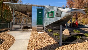 Una estructura metálica con una puerta verde, escalones que la conducen y un pequeño ventanal.