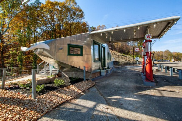 A vintage airplane exhibit with a canopy, a red fuel pump, and a stone pathway. - Airplane Filling Station -Unique Stay in Knoxville (Knoxville)