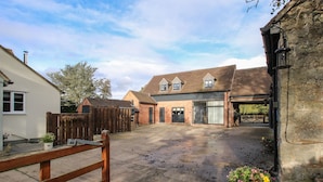 A rural property with a large open driveway, a wooden gate, and a brick building with large windows and a garage. - The Lawley (Shrewsbury)