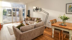 A spacious living area with a sofa, a dining table, and a floor lamp. - The Lawley (Shrewsbury)