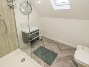 A modern bathroom with a glass shower enclosure, a white sink, and a toilet.