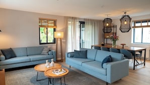 Een moderne woonkamer met een zithoek, een eettafel en een salontafel.